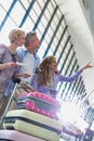 Family on holiday looking at their flights on monitor in airport