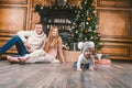 Family holiday New Year and Christmas. Young caucasian family mom dad son 1 year sit wooden floor near fireplace christmas tree on Royalty Free Stock Photo