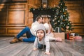 Family holiday New Year and Christmas. Young caucasian family mom dad son 1 year sit wooden floor near fireplace christmas tree on Royalty Free Stock Photo