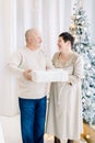 Family, holidays, christmas, mature age concept. Happy middle aged couple in love holding together gift box, while Royalty Free Stock Photo