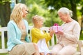 Happy family giving present to grandmother at park Royalty Free Stock Photo