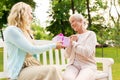 Daughter giving present to senior mother at park Royalty Free Stock Photo