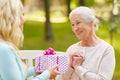 Daughter giving present to senior mother at park Royalty Free Stock Photo