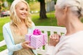 Daughter giving present to senior mother at park Royalty Free Stock Photo