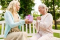 Daughter giving present to senior mother at park Royalty Free Stock Photo