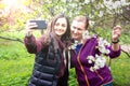 Two women of a friend young and older take a selfie on a smartphone on a background of blooming cherry