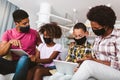 African american family wearing protective masks using digital tablet at home
