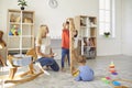 Happy mother with her two children playing with lots of toys and building block tower at home Royalty Free Stock Photo