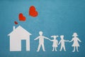Family and home love concept. Paper house and family on blue textured background. Dad, mom, daughter and son hold hands. Royalty Free Stock Photo