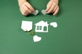 Family home and real estate concept. Close up of child hands holding white paper house and heart on green background. Royalty Free Stock Photo