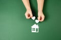 Family home and real estate concept. Close up of child hands holding white paper house and heart on green background. Royalty Free Stock Photo