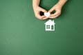 Family home and real estate concept. Close up of child hands holding white paper house and heart on green background. Royalty Free Stock Photo
