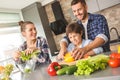 Family at home standing in kitchen together father teaching son cutting vegetables cheerful Royalty Free Stock Photo