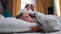 A family in the hotel room - a girl sleeping in bed - her mom and dad looking at her Royalty Free Stock Photo