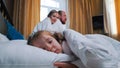 A family in the hotel room - a little girl sleeping in bed - her mom and dad looking at her Royalty Free Stock Photo