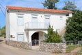 Family house built on street corner with closed window blinds and small front balcony surrounded with paved road next to