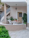 A family house entrance with a small terrace, table and chairs, door and stairway to the next floor.