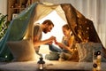 Family playing tea party in kids tent at home