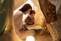 Happy family reading book in kids tent at home Royalty Free Stock Photo