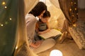 Happy family reading book in kids tent at home Royalty Free Stock Photo