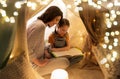 Happy family reading book in kids tent at home Royalty Free Stock Photo