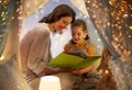 Happy family reading book in kids tent at home Royalty Free Stock Photo