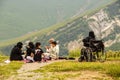 Family in islamic dress with mobile phones - woman in wheelchair sits on cliff of Devil`s