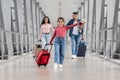 Family Journey. Little Girl Carrying Suitcase While Walking With Parents At Airport