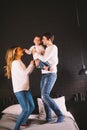 Family Jumping On Bed Together. Family fun. The beautiful family jumping on the bed. Caucasian mom dad and son active Royalty Free Stock Photo