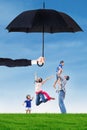 Family jumping under umbrella on the meadow Royalty Free Stock Photo