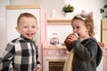 Family and kids concept. Toddler boy smiling and cute little girl eating cake with sugar icing in play kitchen Royalty Free Stock Photo