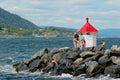 Family with kids enjoy the view to the fjord from a lighthouse at the entrance to the harbor in Drobak, Norway.