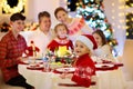 Family with kids having Christmas dinner at tree Royalty Free Stock Photo