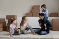 Family with kids resting sit on floor on relocation day