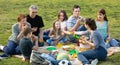 Family with kids talking and eating pizza in park