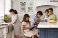 Family In Kitchen Doing Chores And Using Digital Devices Royalty Free Stock Photo
