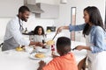 Family In Kitchen At Home Making Pancakes Together