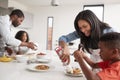 Family In Kitchen At Home Making Pancakes Together