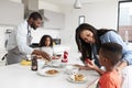 Family In Kitchen At Home Making Pancakes Together