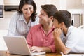 Family in kitchen with laptop smiling Royalty Free Stock Photo