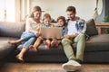 Family, laptop and kids with parents on a living room sofa with education game online. Mom, dad and young children Royalty Free Stock Photo