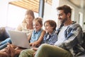 Family, laptop and kids smile with parents on a living room sofa with education game online. Mom, dad and young children Royalty Free Stock Photo