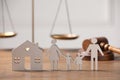 Family law. Figure of parents with children, house model, scales, gavel on wooden table, space for text Royalty Free Stock Photo