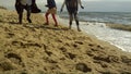 Family legs play beach together at sea shore. Fun people walking by ocean waves.