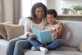 Family leisure activity. Young black mother and little son reading book together Royalty Free Stock Photo