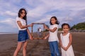 Family, leisure and people concept-asian happy female siblings holding picture of frame of parents on the beach Royalty Free Stock Photo