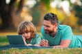 Family, leisure and people concept. Happy father and son with tablet pc computer laying on grass. Kid with daddy Royalty Free Stock Photo