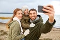 Family taking selfie by smartphone on autumn beach
