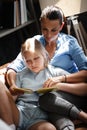 Family leisure time concept. Happy beautiful woman and teenage girl reading a book sitting on a couch indoors. Mother Royalty Free Stock Photo