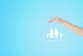 Female hand protecting white family icons with blue background.
